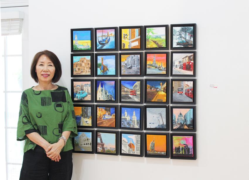 박영숙 대표가 본인의 작품 Miniature city series (6x6인치, 오일 캔버스)에서 포즈를 취하고 있다. 
