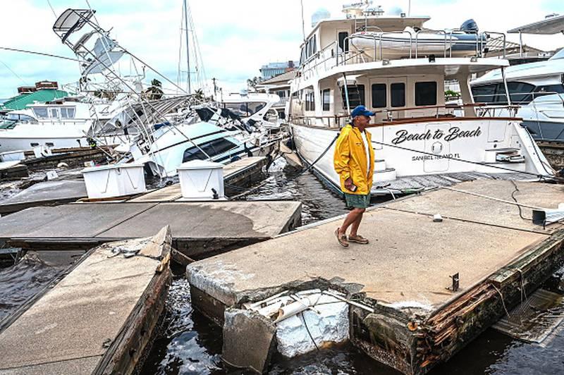 한 남성이 2022년 9월 29일 플로리다 포트마이어스에서 허리케인 이안의 여파로 보트가 부분적으로 물에 잠기면서 정박지의 손상을 검사하고 있다.
