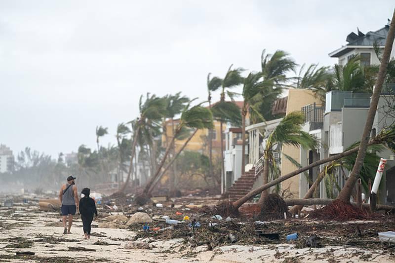 플로리다주 보니타 스프링스에서 사람들이 2022년 9월 29일 허리케인 이안으로 인해 피해를 입은 건물을 바라보며 해변을 걷고 있다. 