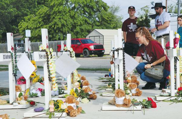  텍사스주 유밸디 초등학교 총기참사 1주년이 된 24일 당시 사건 현장 인근에 희생자들의 이름이 적힌 십자가와 꽃다발 등이 놓인 가운데 주민들이 추모하고 있다. [로이터]