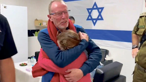 하마스에게 납치됐던 이스라엘 소녀 에밀리 핸드가 26일 풀려나 아버지와 재회의 포옹을 하고 있다. [로이터]