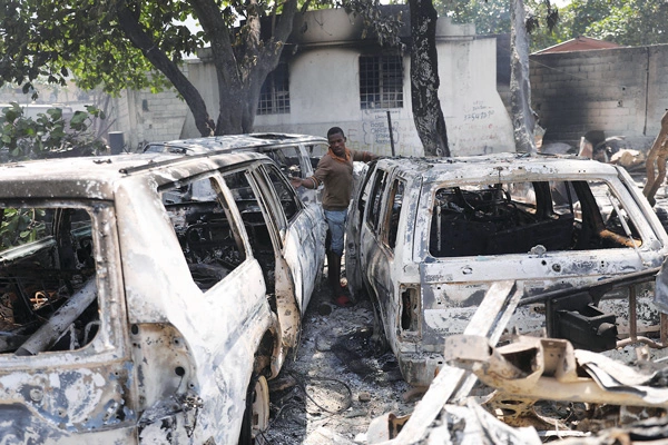  폭력 사태가 난무하고 있는 아이티에서 지난 25일 갱단들의 방화로 전소된 차량들을 한 주민이 망연자실 바라보고 있다. [로이터]