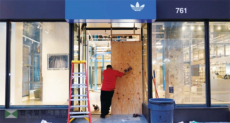  이민단속 반발 시위와는 별도로 지난 10일 밤 LA 다운타운 브로드웨이 선상에서 약탈 행위가 기승을 부려 상당수의 업소와 매장들이 피해를 입었다. 밤새 출입문과 유리창이 박살난 아디다스 매장에서 11일 인부들이 보수 작업을 하고 있다. [로이터]