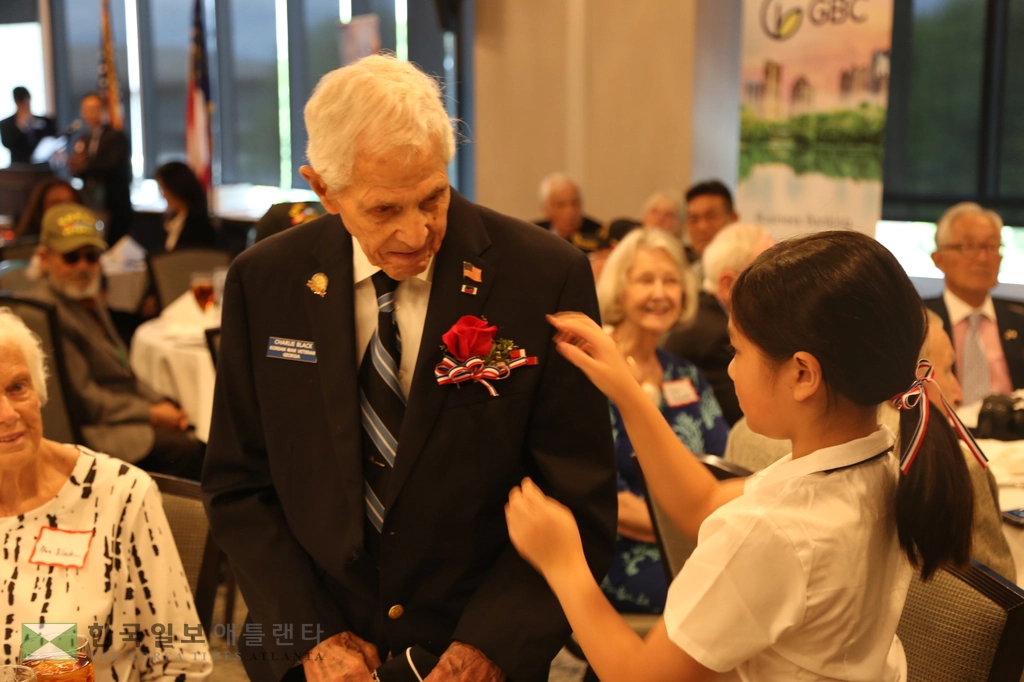 한국전 참전용사에게 아틀란타 연합장로교회 어린이 합창단 학생이 감사의 꽃을 달아주고 있다.
