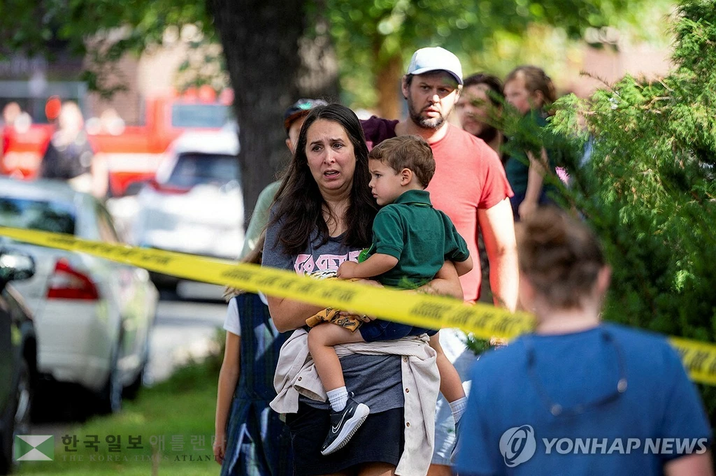 27일 미네소타주 미니애폴리스 초등학교에서 발생한 총기사건 후 한 아이가 아이를 끌어안고 사건 현장을 바라보고 있다.[로이터 연합뉴스 자료사진.]