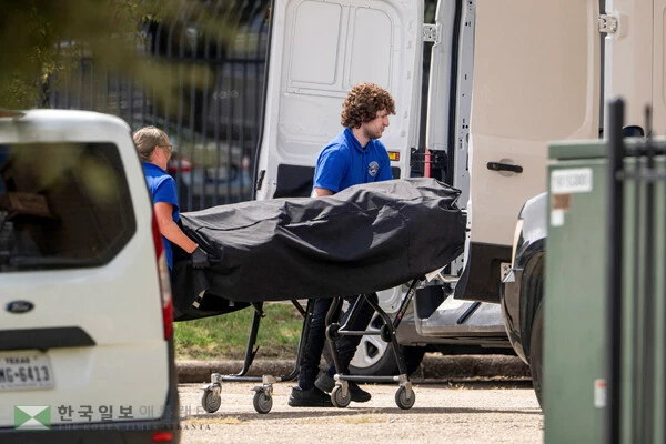 24일 텍사스주 댈러스에 있는 이민 및 세관 집행국(ICE) 현장 사무소에서 검시관 사무실 직원들이 총격 사건 현장에서 용의자의 시신을 밴 뒷좌석에 싣고 있다. [로이터]