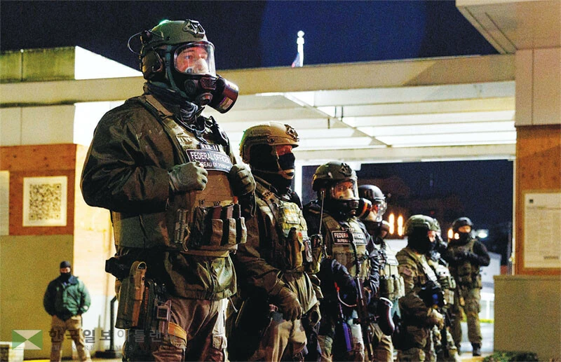  무장한 연방 요원들이 오리건주 포틀랜드의 ICE 건물 앞에서 경비를 서고 있다. [로이터]