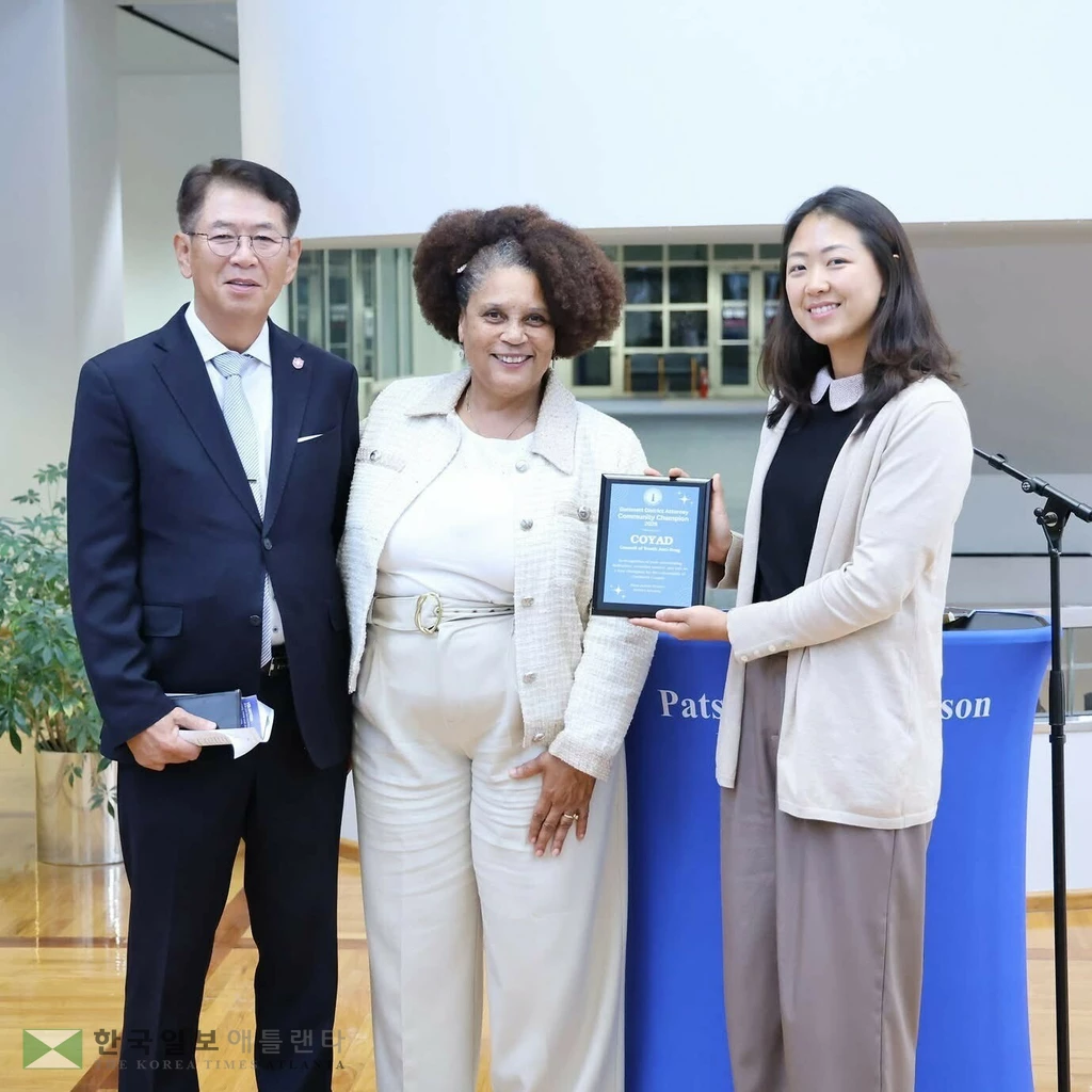 팻시 오스틴-갯슨 귀넷 검사장이 코야드 폴림 대표와 관계자에게 커뮤니티 챔피언 상패를 수여하고 있다.