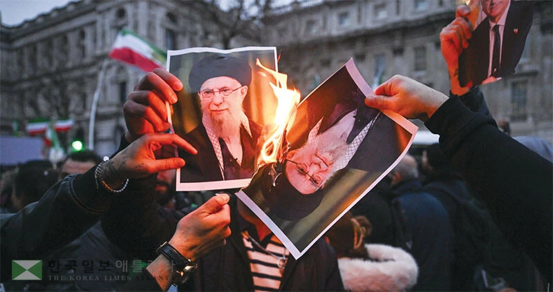  11일 영국 런던에서 열린 이란 정부에 대한 항의시위에서 참가자들이 이란 최고지도자 아야톨라 하메네이의 사진을 불태우고 있다. [로이터]