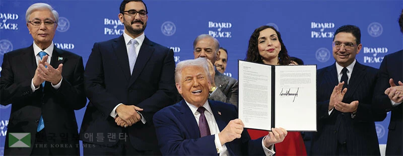도널드 트럼프 대통령이 22일 평화위원회 출범 서명식에서 서명한 문서를 들어보이고 있다. [로이터]
