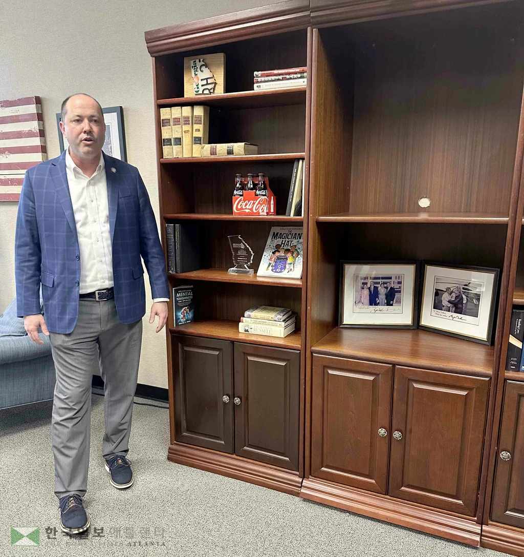 크리스 카 조지아주 주지사 후보가 법률 서적이 꽂힌 자신의 책장 옆에 서서 설명하고 있다.