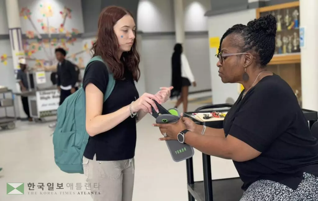 조지아 하인즈빌 리버티 고교 학생이 수업 전 휴대전화를 보관장치에 넣고 있다. 이 학교는 자체적으로 휴대전화 제한 조치를 시행 중이다. <사진=GPB>