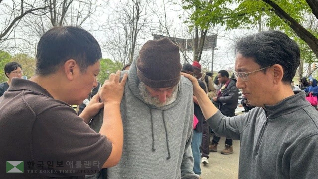 지난 4일 애틀랜타 다운타운에서 디딤돌선교회와 지역교회들이 연합해 부활절 나눔 돌봄축제를 실시했다. 봉사자들이 한 노숙자를 위해 기도하고 있다.