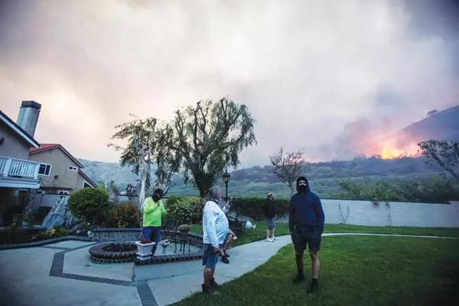 지난해 오렌지카운티 요바린다 시에서 발생한‘블루릿지’ 산불을 주민들이 뒷마당에서 걱정스럽게 바라보고 있다. &lt;로이터>