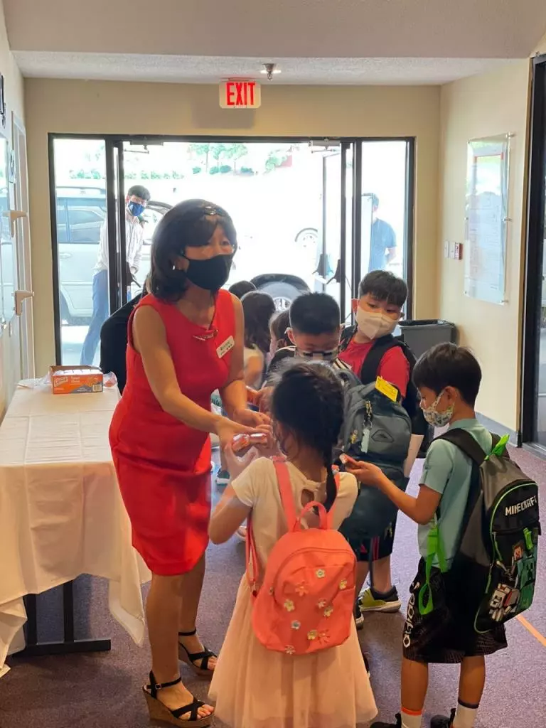 섬기는 한국학교 송해순 교감이 21일 가을학기 첫 등교하는 학생들을 맞고 있다.