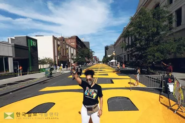 &nbsp;‘흑인 목숨도 소중하다(BLM)’ 벽화와 글씨가 새겨진 도로에서 한 흑인 여성이 시위를 벌이고 있다. [로이터]