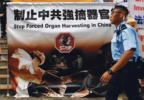  중국 정부의 신도 대상 장기 적출 행위에 항의하기 위해 법륜공 단체가 홍콩 거리 걸어 놓은 배너 옆으로 경찰이 지나가고 있다. [로이터]
