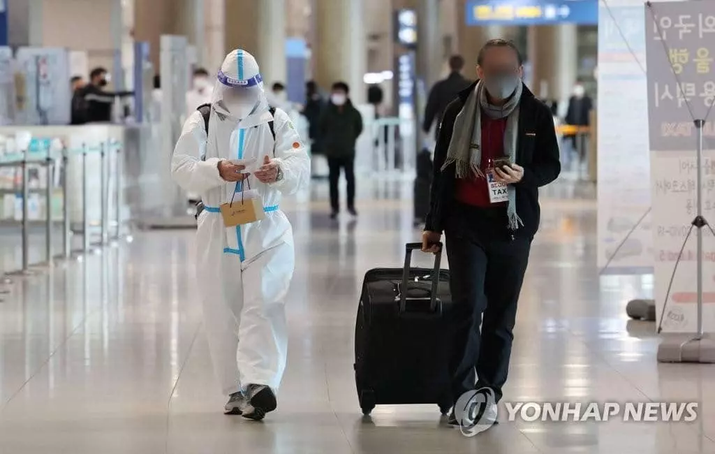 23일 인천국제공항 제1터미널 입국장에서 방역복을 착용한 한 해외 입국자가 이동하고 있다. 방역 당국은 코로나19 오미크론 변이 유행이 확산하면서 해외 유입을 통한 오미크론 확산을 막기 위해 입국자 방역 관리 조치를 한층 강화하기로 했다.