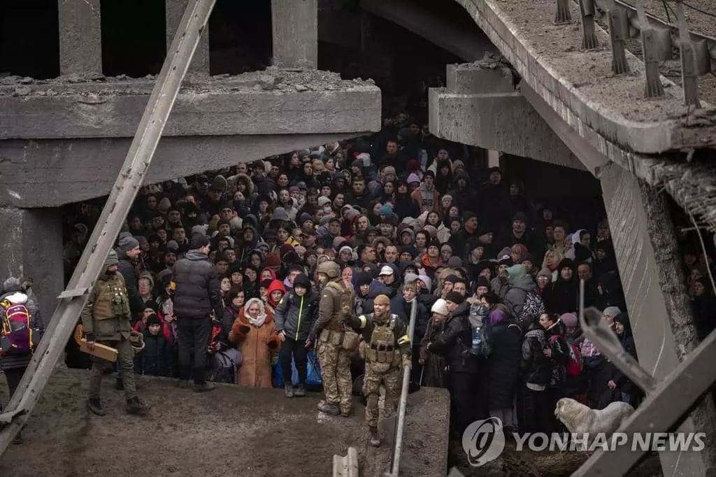  5일(현지시간) 우크라이나 수도 키이우(키예프) 외곽 이르핀강을 건너 피란하려는 주민들이 러시아군의 폭격으로 파괴된 다리 아래 모여 있다.