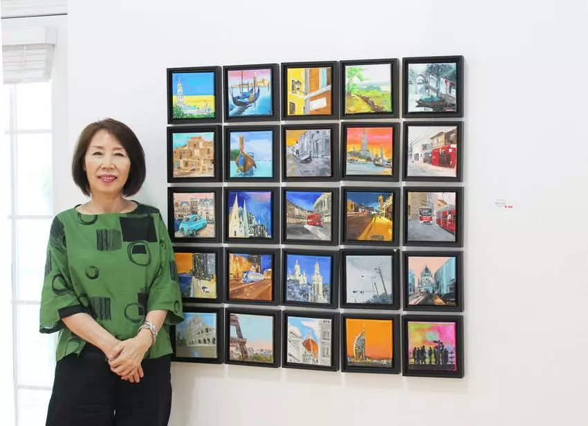 박영숙 대표가 본인의 작품 Miniature city series (6x6인치, 오일 켄버스)에서 포즈를 취하고 있다. 
