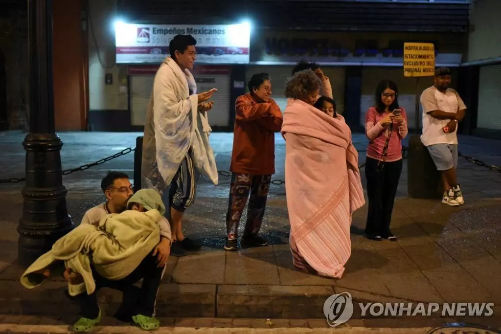 22일(현지시간) 멕시코 수도 멕시코시티에서 주민들이 서부에서 발생한 강진에 놀라 이불 등으로 몸을 감싼 채 거리에 대피해 있다.