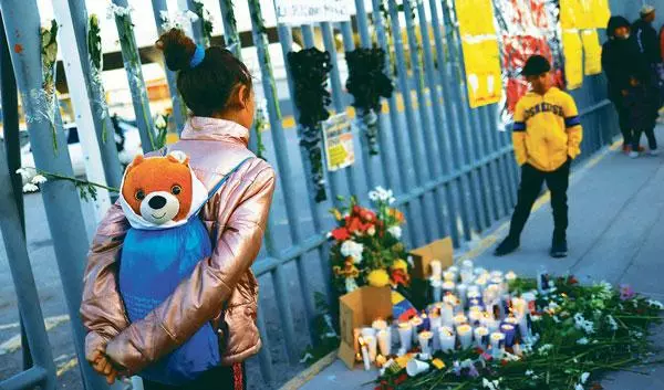  지난 28일 화재로 40명이 사망하는 참사가 발생한 국경 이민자 수용소 앞에 추모의 꽃과 촛불들이 놓여 있는 가운데 난민 어린이들이 이를 지켜보고 있다. [로이터]