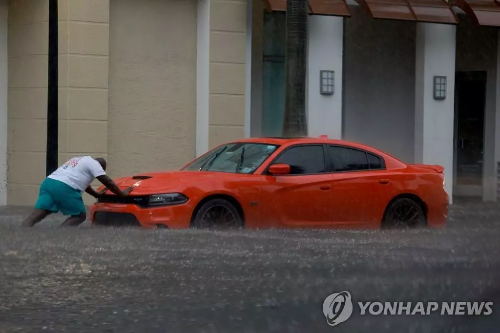 12일 폭우로 물에 잠긴 플로리다주 다니아비치의 거리에서 한 시민이 자동차를 밀고 있다. 플로리다주를 강타한 이번 폭우로 할리우드, 다니아비치 등 일부 지역이 홍수 피해를 봤다. 