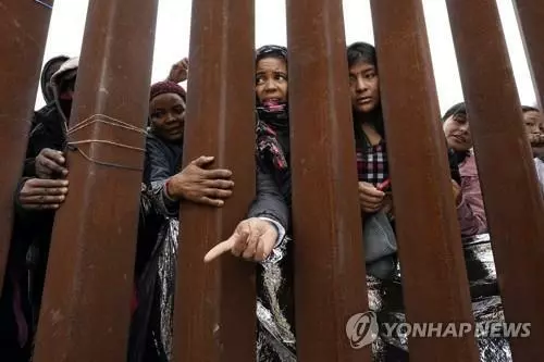 국경 장벽 앞 이주민들[AP 연합뉴스 자료사진. 재판매 및 DB 금지]