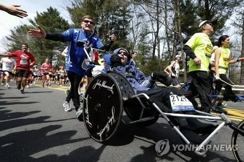 지난 2013년 4월 15일 휠체어에 탄 릭 호이트가 아버지 딕 호이트(가운데 왼쪽)와 함께 보스턴 마라톤 대회에서 달리고 있다. AP 통신에 따르면 릭 호이트는 2년 전 작고한 아버지를 따라 호흡기 합병증으로 22일 세상을 떠났다.