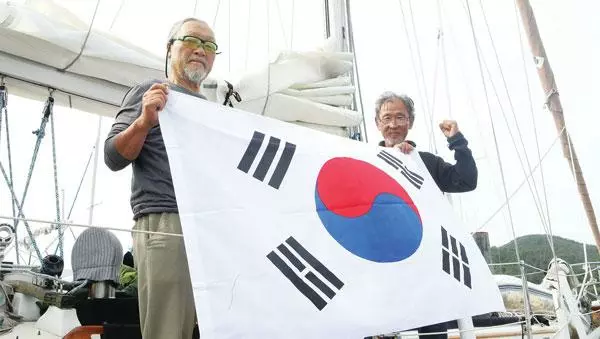  LA에서 출발한지 84일 만인 한국시간 27일 오전 한국 입국신고 기착지 통영에 입항한 남진우(오른쪽) 선장과 유도열 대원이 태극기를 들고 마침내 한국땅에 도착했음을 알리고 있다. [연합]