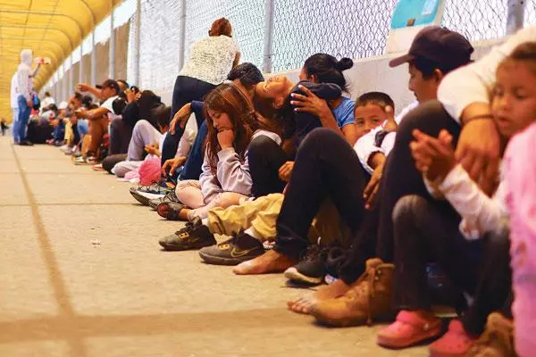 미국 국경에서 난민 신청을 하려는 중남미인들이 지난달 멕시코 시우다드후아레스에서 미국으로 넘어가는 다리에 줄을 지어 앉아 대기하고 있다. [로이터]