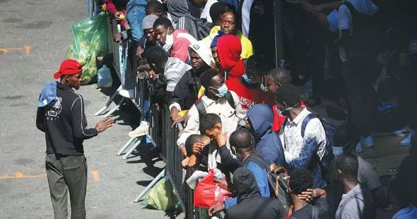  텍사스주 국경을 넘어온 망명 희망자들 중 뉴욕으로 이송된 이민자들이 수용 시설인 맨해튼의 한 호텔 앞에 몰여 있다. [로이터]