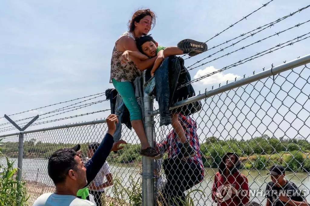 지난달 25일 미국-멕시코 국경 지역 철제 펜스를 위태롭게 넘어가는 이민자들[AFP 연합뉴스 자료사진. 재판매 및 DB 금지]