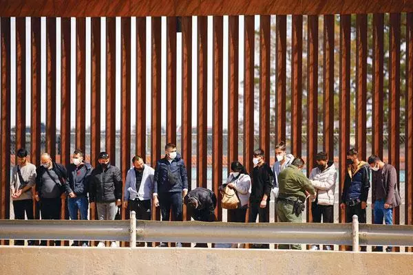  지난해 텍사스주 국경장벽 앞에서 국경수비대 요원이 난민 신청 이민자들을 조사하고 있는 모습. [로이터]